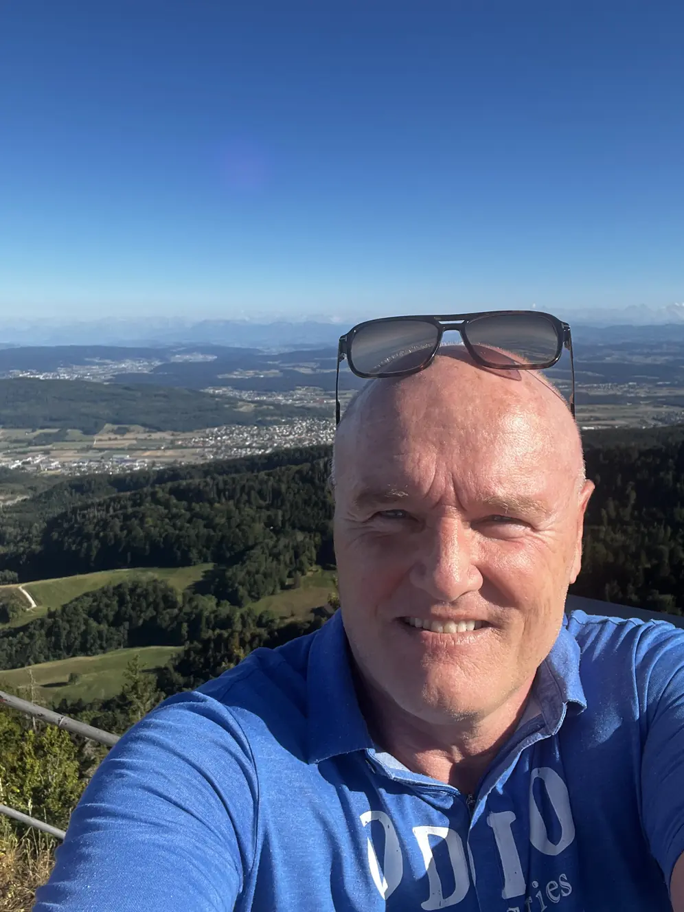 Lächelnder Mann über 60 auf einem Aussichtspunkt in den Schweizer Bergen